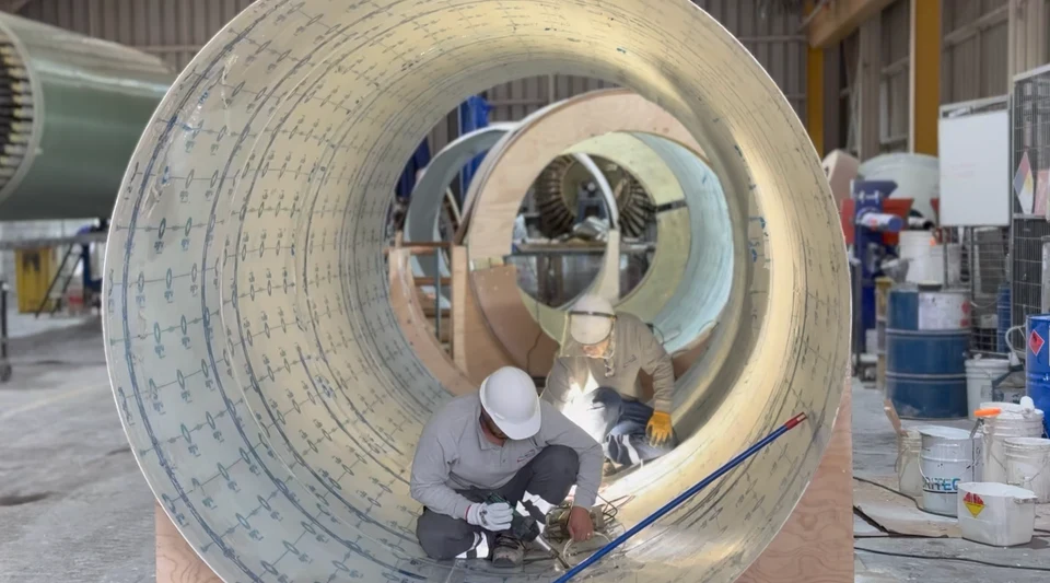 Vista interior de un tramo de gran diámetro en FRP, con trabajadores realizando labores dentro de la pieza.