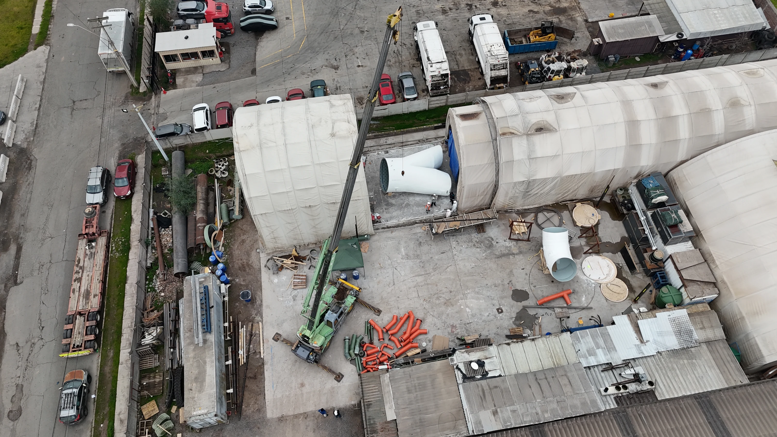 Vista aérea del patio de la planta, con una grúa móvil, las carpas de fabricación y piezas de gran diámetro en distintas etapas.