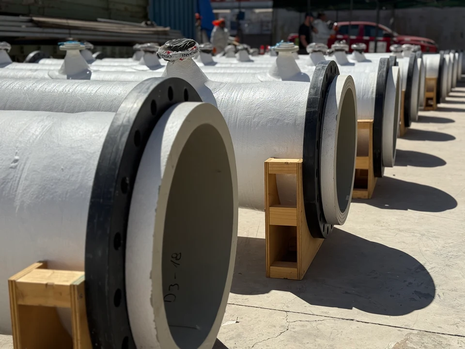 Fila de spools embridados en FRP apoyados sobre tacos de madera en el patio, listos para despacho.