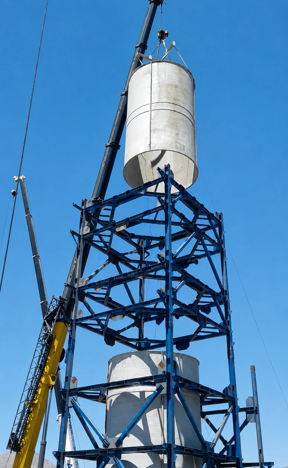 Grúas montando un cuerpo cilíndrico sobre la estructura de acero de la torre desulfurizadora.